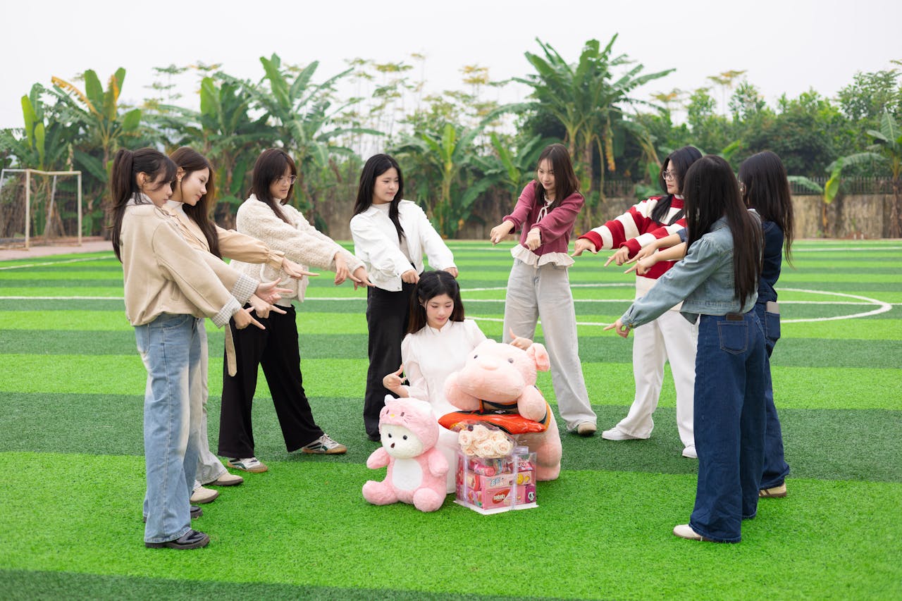 A group of young women gather around toys in an outdoor field in Hanoi.