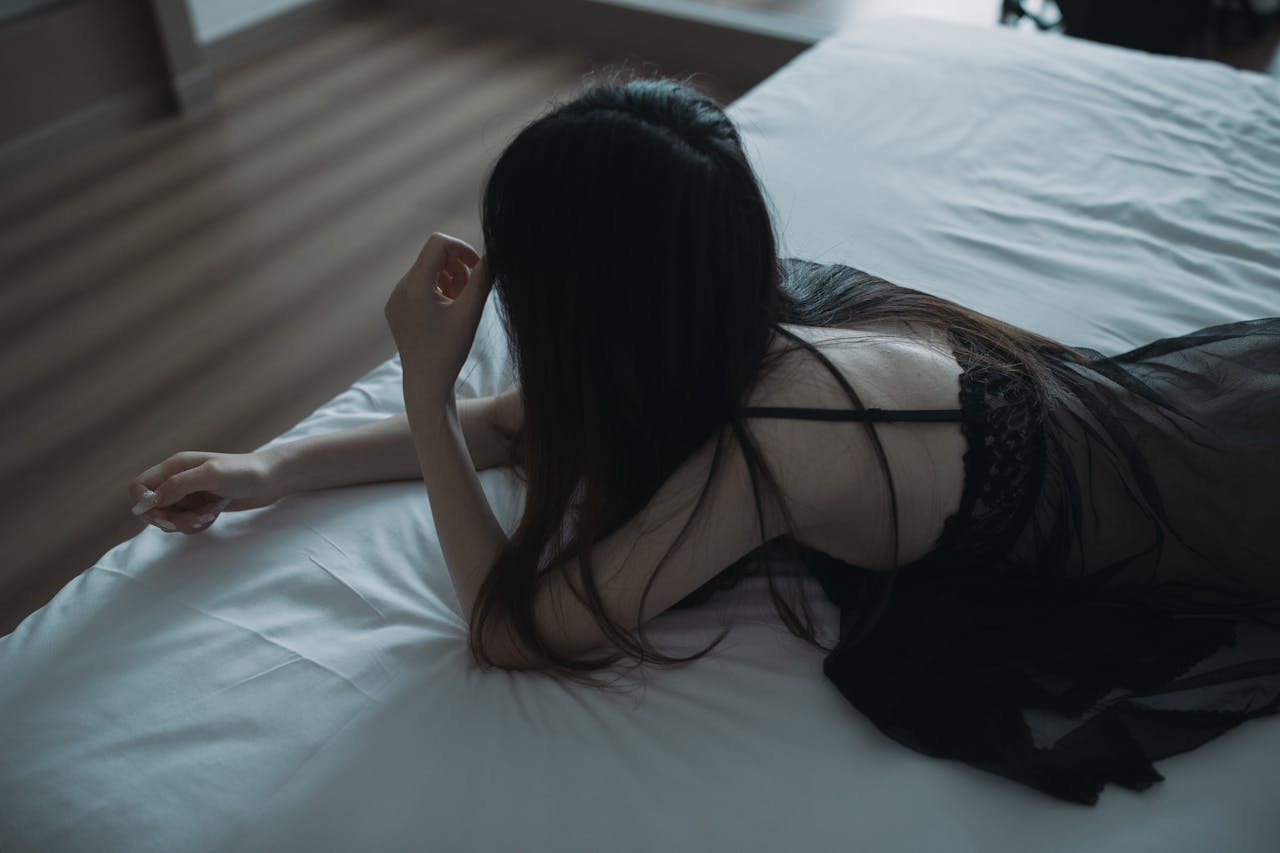 Woman in black nightwear lying on a bed, creating a serene and intimate atmosphere.